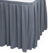 A slate blue Snap Drape box pleat table skirt on a table with pleated edges.