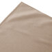 A beige shirred pleat Snap Drape table skirt on a table.