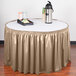 A table with a Snap Drape beige shirred pleat table skirt on it with a tray of food.