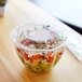 A clear plastic Eco-Products salad container with a lid holding salad.
