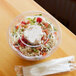 A clear Eco-Products compostable plastic salad bowl with salad and a fork in it.