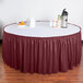 A table with a burgundy shirred pleat skirt on it.