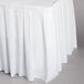A white box pleat table skirt on a table with a white tablecloth.