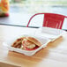 A chicken sandwich and fries in a white Eco-Products compostable takeout container.