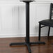 A black table leg for a BFM Seating counter height table with a black chair
