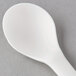 An Eco-Products Plantware white compostable plastic soup spoon on a gray surface.