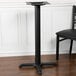 A black table base with a black pole and a black table on it.