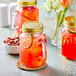 A group of Acopa Rustic Charm mason jars filled with red drinks and lime slices on a counter.