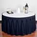 A table with a navy Snap Drape table skirt on it with a tray of drinks.