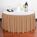 A table with a Snap Drape Sandalwood box pleat table skirt over a white tablecloth and a tray of food.