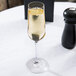 A Stolzle Revolution flute glass filled with champagne on a table.