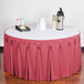 A table with a Snap Drape Dusty Rose Bow Tie Table Skirt on a table with a white tablecloth and a tray of drinks.