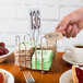A Tablecraft chrome plated jelly packet rack holding forks and napkins.