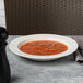 A Libbey Royal Rideau white porcelain soup bowl filled with tomato soup on a table.