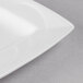 A close up of a white Libbey rectangular porcelain plate with a curved edge.