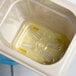 A Cambro 1/8 size amber plastic drain tray with yellow liquid inside.