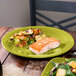 A Fiesta® Lemongrass China round chop plate with salmon and vegetables on a table.