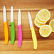 A Victorinox 4-piece paring knife set with colorful handles on a wooden surface with lemon slices.