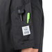 A close-up of a black Chef Revival chef jacket pocket with green pen and flashlight in it.