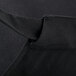 A close up of a black poly-cotton Chef Revival bib apron with a pocket.