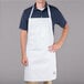 A man wearing a white Chef Revival bib apron with one pocket.