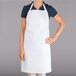 A woman wearing a white Chef Revival bib apron with a pocket.