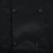 A close up of a black Chef Revival long sleeve chef jacket with buttons.