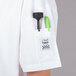 A Chef Revival white short sleeve chef jacket with a knife and green pen in the pocket.