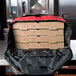A stack of pizza boxes in a red Rubbermaid insulated delivery bag.