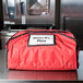 A red Rubbermaid ProServe insulated delivery bag on a counter.