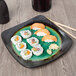 A Libbey stoneware plate with sushi and chopsticks on a wood table.