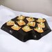 A GET Stone-Mel melamine display tray with appetizers on a table.