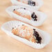 A row of Hoffmaster white fluted eclair baking cases filled with three pastries.