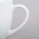 A close up of a Tuxton porcelain white mug with a handle.