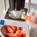 A person using a Vollrath Redco 8 section core replacement blade assembly to core a tomato.