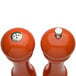 Two Chef Specialties orange pepper mills with a salt shaker on top.