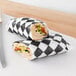 A sandwich wrapped in black and white Choice deli wrap paper.