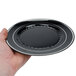 A hand holding a Fineline black plastic plate with silver bands.