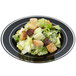 A black Fineline plastic plate with a silver band filled with a salad.