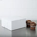 A white bakery box with two cupcakes on top.