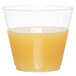 A close up of a WNA Comet Classicware clear plastic fluted tumbler filled with orange juice.