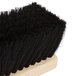 A close-up of a Carlisle Tampico broom head with black bristles and a wooden handle.