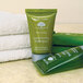 A green bottle of Basic Earth Botanicals Conditioning Shampoo next to a stack of towels.