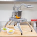 A Nemco Easy Onion / Fruit / Vegetable Slicer II on a counter with bowls of limes and lemon slices.