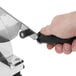 A close-up of a hand using a Tellier countertop bread slicer with a black handle.