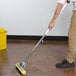 A person using a Carlisle foam sponge mop to clean a hardwood floor.