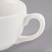 A close-up of a Libbey ivory porcelain coffee cup with a handle.