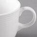 A close up of a white porcelain tea cup with a handle.