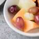 A white Reserve by Libbey porcelain bowl filled with fruit including grapes and melon.