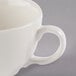 A close up of a Libbey ivory porcelain coffee cup with a handle.